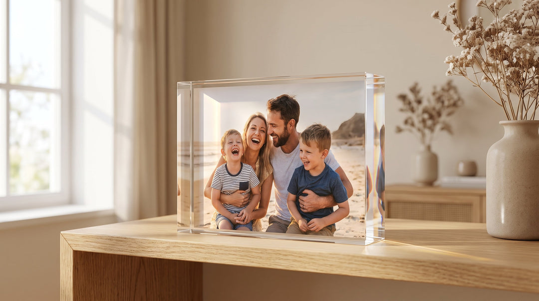 Acrylic photo block displaying a family beach portrait on a wooden shelf beside a vase of dried flowers.