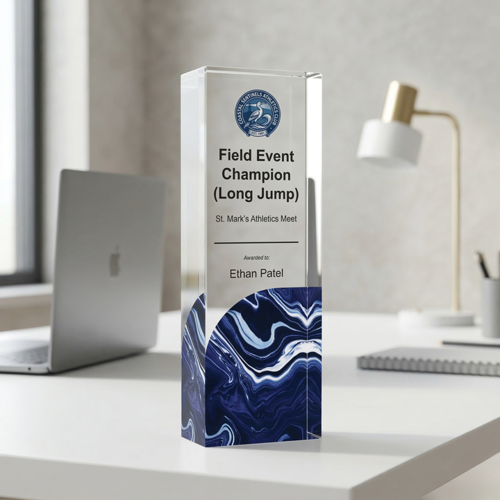 Tall, clear glass award with blue marbled base on a desk
