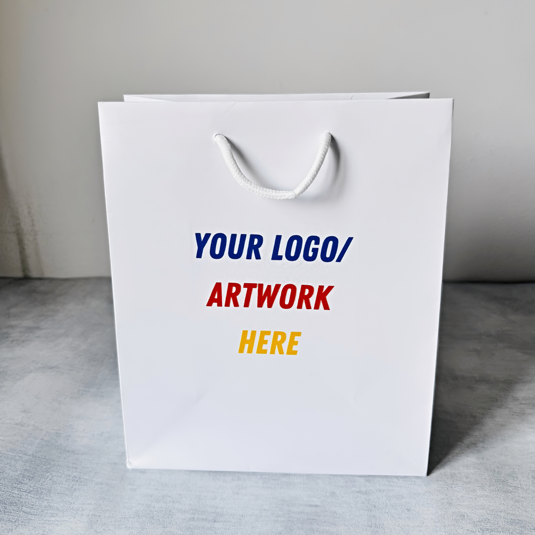 White paper bag with text 'YOUR LOGO/ ARTWORK HERE' on a gray surface