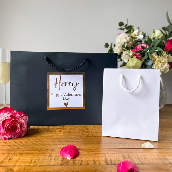 A large size black valentines day gift bags and a medium valentines day gift bags with the rose flower in the table