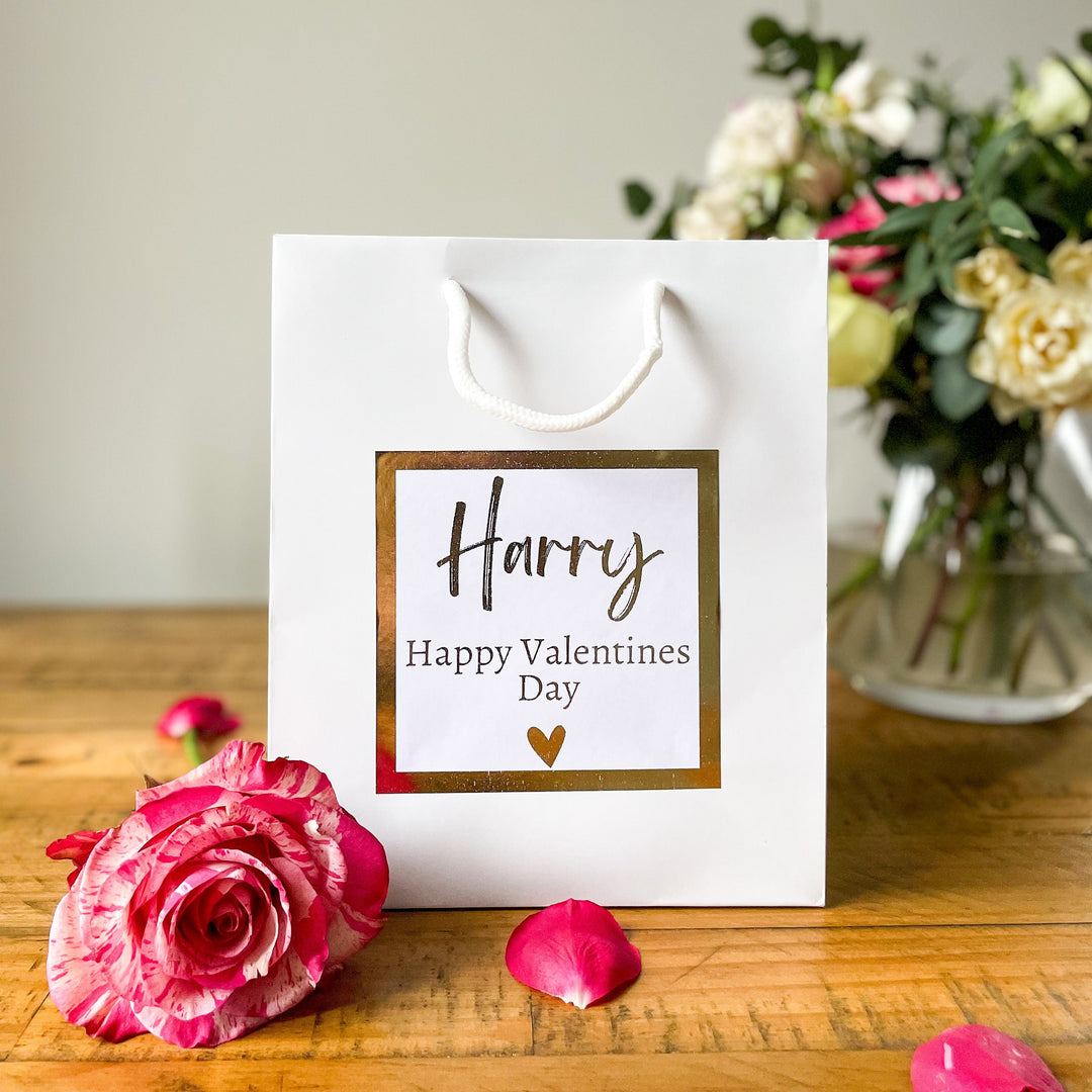 A white valentines day gift bags with premium handle and gold foil stickers prints "Happy valentine's day"