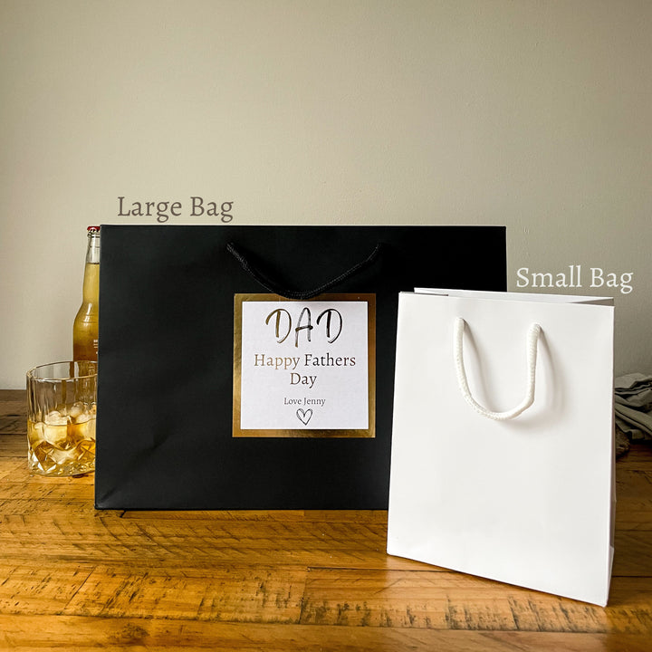 large black and small white father's day gift bags with a gold-trimmed label that reads "DAD Happy Father's Day" and is signed "Love Jenny."