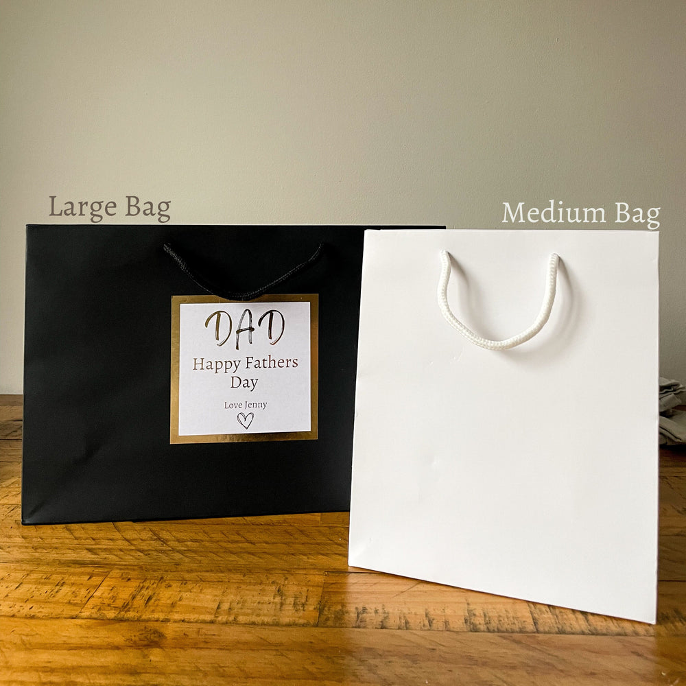 black and white father's day gift bags with a gold-trimmed label that reads "DAD Happy Father's Day" and is signed "Love Jenny."