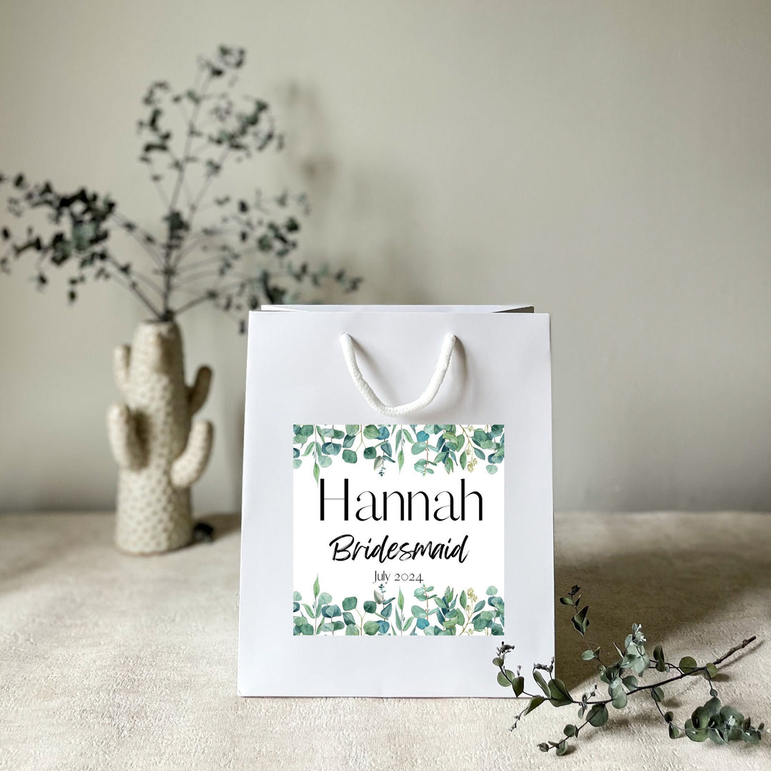 A white hen party gift bags with premium handels and the premium stickers name Hannah for wedding favor bags
