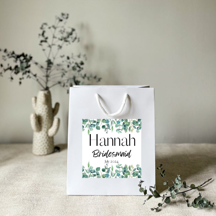 A white hen party gift bags with premium handels and the premium stickers name Hannah for wedding favor bags
