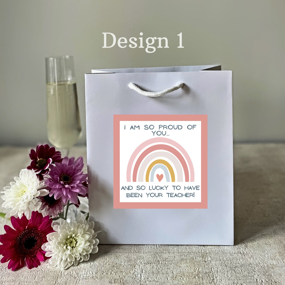 A silver luxury teacher gift bag with a personalised 'Thank You' sticker attached, presented alongside colourful flowers.